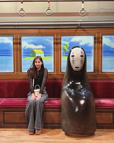 a woman sitting on a bench next to a large animal statue in front of a window