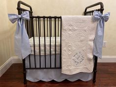 a baby crib with a blue and white blanket on it's side, next to a wooden floor