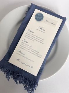 a white plate topped with a blue napkin and a menu card on top of it