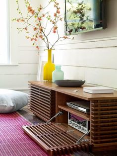 a wooden entertainment center with a radio on top of it next to a vase filled with flowers