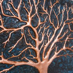 a close up of a metal tree on a black background with copper foiled leaves