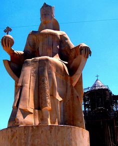 a statue of a man holding a bird in his right hand and sitting on top of it