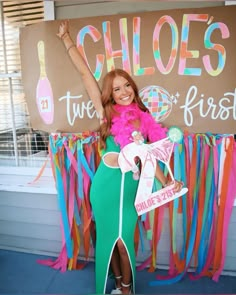 a woman in a green dress standing next to a sign