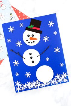 a snowman made out of paper on top of a blue background with white snowflakes