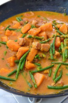 a skillet filled with meat and veggies on top of a white table