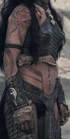 an image of a woman with tattoos on her chest and arm, wearing leather armor