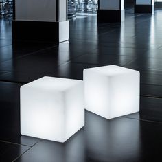 two illuminated cubes on the floor in an empty room