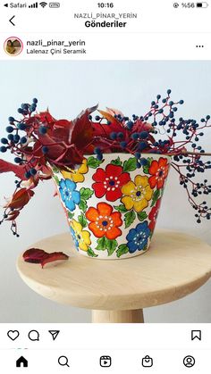 a flower pot with red and yellow flowers in it sitting on a table next to an instagram post