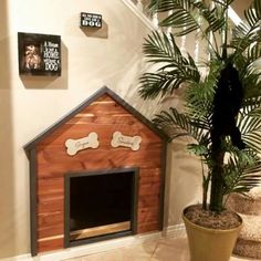 a dog house made out of wood with a potted plant next to it and pictures on the wall