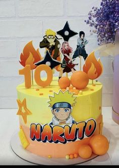 a birthday cake decorated with anime characters and oranges on a table next to a potted plant