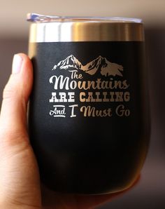 a hand holding a wine glass with the words mountains are calling and i must go