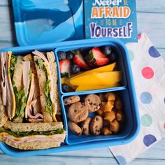 a blue lunch box filled with sandwiches and fruit