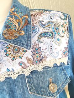 the back of a jean jacket with an embroidered design on it and lace trimmings