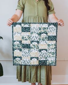 a woman holding up a green and white quilt