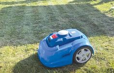 a blue lawn mower sitting on top of a lush green grass covered field next to a red fire hydrant