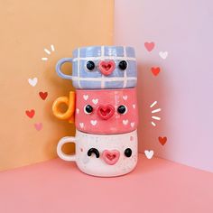 two mugs with faces are stacked on top of each other in the shape of hearts