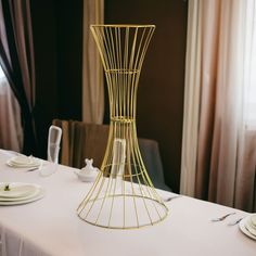 a white table with plates and silverware on it in front of a curtained window