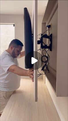 a man is holding the back of a surfboard in front of a wall mounted tv