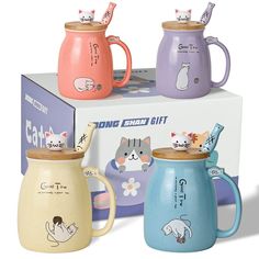 three ceramic mugs with cats on them are sitting in front of a cardboard box