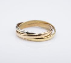 This petite ring features three interlocking band in rose, white, and yellow gold.  The trinity ring represents fidelity, friendship, and love.  Perfect as a wedding band, or fun right-hand ring. Metal Type:  18k Tricolor Gold Notable Marks: 18k ZV Measurements: Size 5.25; 2.5 mm band width tapering to 1.1 mm Condition: Very good condition. Jewelry Disclosure: We want you to love any piece you purchase from us. Please note that the majority of our jewelry items are pre-owned unless otherwise stated. This means they have the usual aspects of pre-owned jewelry, such as light signs of wear or patina. Vintage and antique gems may display light wear to facets commensurate for age. If there is a major dent, ding, flaw, or chip, it will be noted in the description. Please review all photos carefu Tri Color Ring, Trinity Ring, Petite Ring, The Trinity, Right Hand Rings, Hand Ring, Ring Metal, Light Display, Lighted Signs