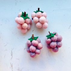 three small pink grapes with green leaves on them