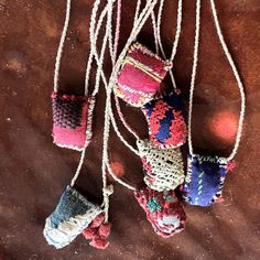 several small knitted objects hanging from strings on a brown surface with other items in the background