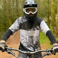 a man riding on the back of a dirt bike down a forest road with trees in the background