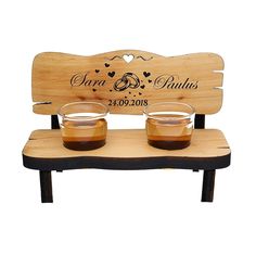 two shot glasses on a wooden bench with the names of their wedding rings and date