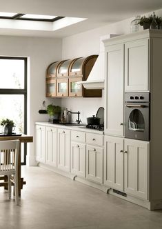 a large kitchen with white cabinets and wood accents on the walls, along with a dining room table