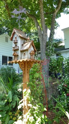 a bird house sitting on top of a wooden pole in the middle of a garden