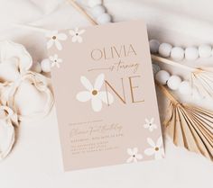 a pink and white floral birthday party card on a table with shells, seashells and palm leaves