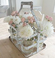 an old metal basket with flowers in it on a wooden table next to a white chair