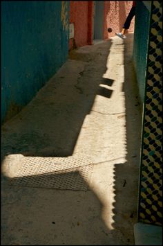 the shadow of a person walking down an alley way