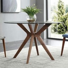 a glass table with wooden legs and a potted plant