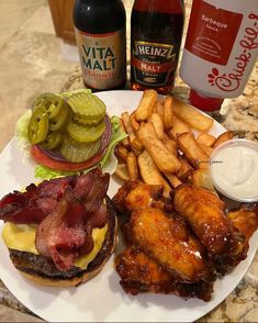 a white plate topped with a burger and fries next to two bottles of booze