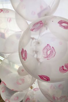 balloons with lipstick drawn on them in the shape of lips are hanging from a ceiling