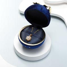 an open blue velvet ring box with a diamond necklace in it on a white surface