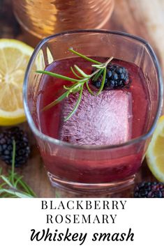 a glass filled with liquid next to sliced lemons and blackberries