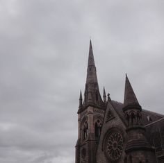 an old church with steeples on a cloudy day