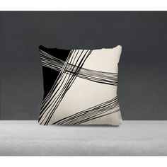 a black and white pillow sitting on top of a gray floor next to a wall