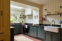 a kitchen with green cabinets and black counter tops is seen from the doorway to the dining room