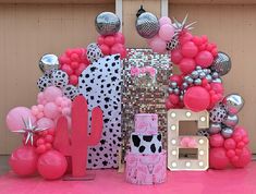 pink and silver decorations on display in front of a wall with mirrors, balloons, and letters