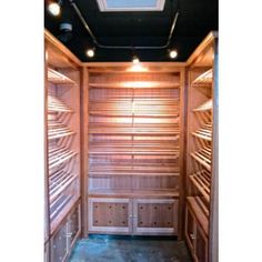 the inside of a wooden storage room with lots of shelves and lights on each side