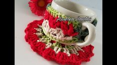 there is a crocheted cup and saucer set on the table with flowers