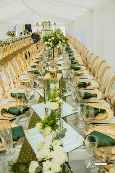 a long table set up with place settings and green napkins for guests to eat