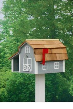 a bird house with a red door on the roof and a tree in the background