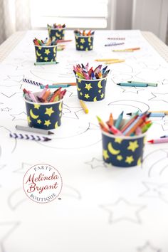 pencils and crayons in cups on a table