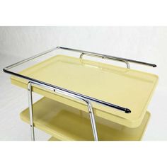 a yellow serving cart with two trays on each side and one holding a silver handle