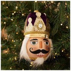 a christmas ornament hanging from a tree with lights in the background and an image of a man's face painted on it