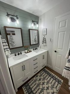 a bathroom with two sinks, mirrors and rugs on the floor in front of it